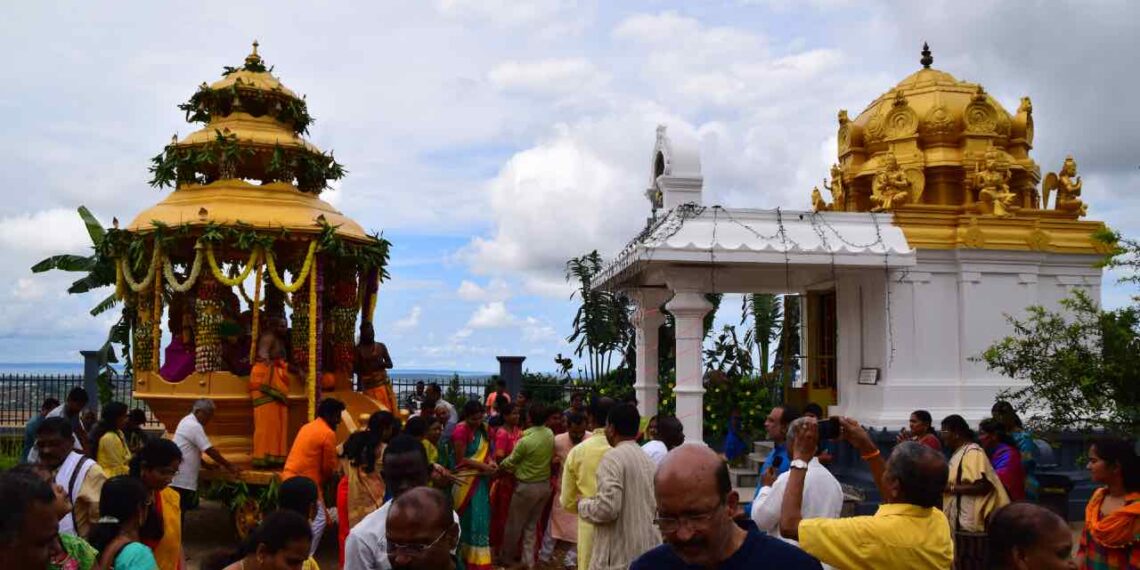 ಉಗಾಂಡದ ಸಪ್ತಗಿರಿ ಶ್ರೀ ವೆಂಕಟೇಶ್ವರ ದೇವಸ್ಥಾನದ ಆವರಣದಲ್ಲಿ ನಡೆಯುತ್ತಿರುವ ರಥೋತ್ಸವದ ದೃಶ್ಯ. ಭಕ್ತರು ಸಂಭ್ರಮದಿಂದ ರಥ ಎಳೆಯುತ್ತಿರುವುದು ಮತ್ತು ಹಿನ್ನೆಲೆಯಲ್ಲಿ ಸುಂದರವಾದ ಚಿನ್ನದ ಬಣ್ಣದ ಗೋಪುರ.
