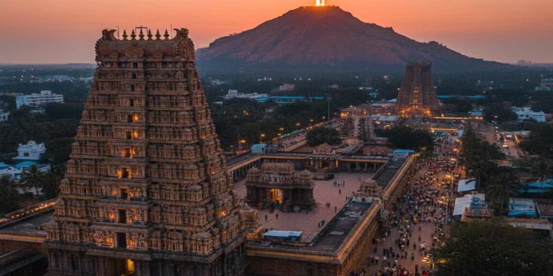A scenic aerial view of Tiruvannamalai Arunachaleswarar Temple with the sacred Arunachala Hill in the background during sunset.