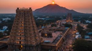 A scenic aerial view of Tiruvannamalai Arunachaleswarar Temple with the sacred Arunachala Hill in the background during sunset.