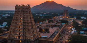 A scenic aerial view of Tiruvannamalai Arunachaleswarar Temple with the sacred Arunachala Hill in the background during sunset.