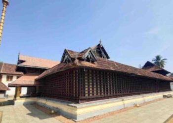 Traditional Kerala style architecture of Thiruvaruppu Sri Krishna Temple in Kottayam with a golden sanctum and tiled roof under a clear blue sky