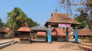 Entrance and courtyard view of the ancient Thiruvizha Mahadeva Temple in Alappuzha, Kerala, featuring traditional Kerala style architecture with tiled roofs and blue pillars.