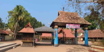 Entrance and courtyard view of the ancient Thiruvizha Mahadeva Temple in Alappuzha, Kerala, featuring traditional Kerala style architecture with tiled roofs and blue pillars.