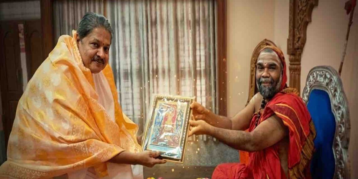 Well-known astrologer Kapu Prakash Ammannaya receiving a framed traditional painting as a gift from a revered Hariharapura Mutt Swamiji in a traditional setting.