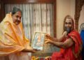 Well-known astrologer Kapu Prakash Ammannaya receiving a framed traditional painting as a gift from a revered Hariharapura Mutt Swamiji in a traditional setting.