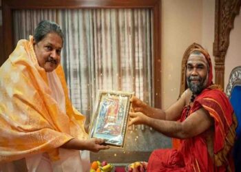 Well-known astrologer Kapu Prakash Ammannaya receiving a framed traditional painting as a gift from a revered Hariharapura Mutt Swamiji in a traditional setting.