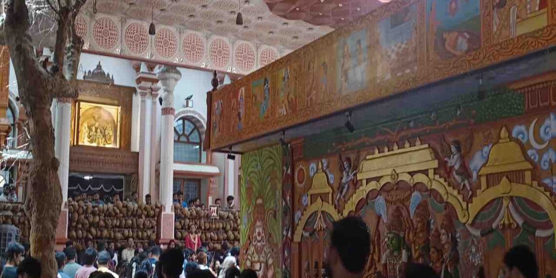 An interior shot of the Karya Siddhi Anjaneya Temple in Bangalore, showing a large crowd of devotees and ornate temple decorations.