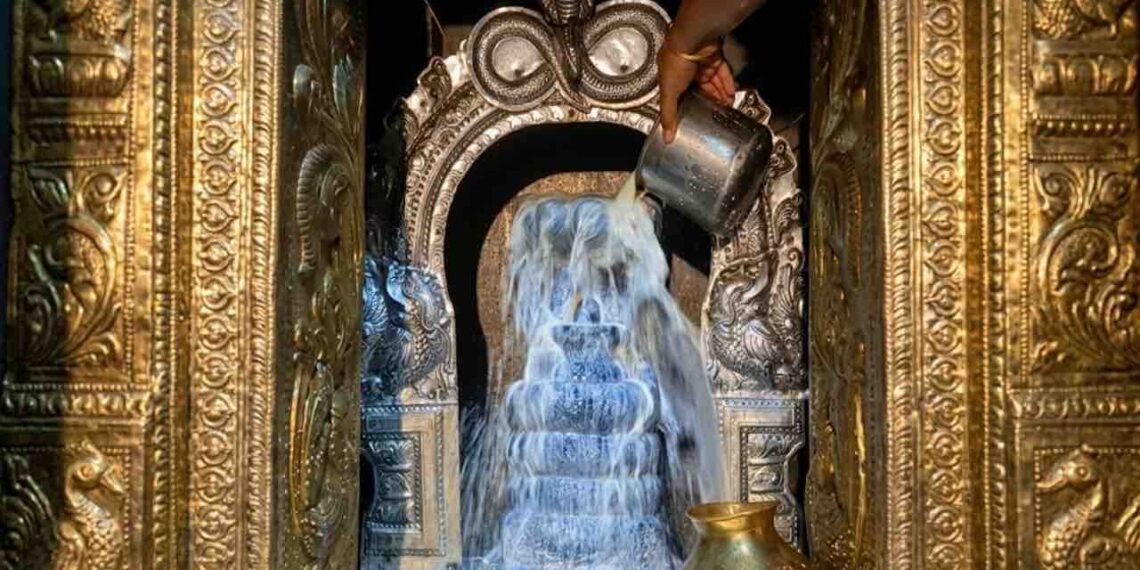 Close-up photograph of a milk abhishekam being performed on a Shiva Lingam at Thirupampuram Seshapureeswarar Temple, showing a hand pouring milk.