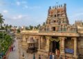 A detailed wide shot of the Satyandheshwara Swamy Ganapati Temple near Kumbakonam, Thanjavur, showing its colourful Dravidiyan gopuram and granite walls in daylight.