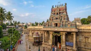 A detailed wide shot of the Satyandheshwara Swamy Ganapati Temple near Kumbakonam, Thanjavur, showing its colourful Dravidiyan gopuram and granite walls in daylight.