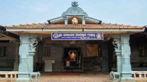 Front entrance view of the traditional Shri Vinayaka Temple in Guddattu, featuring a tiled roof, carved pillars with elephant figures, and a Kannada signboard.