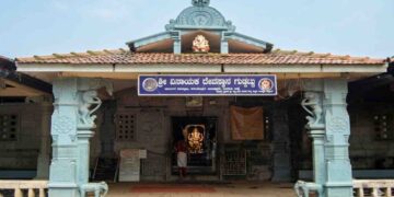 Front entrance view of the traditional Shri Vinayaka Temple in Guddattu, featuring a tiled roof, carved pillars with elephant figures, and a Kannada signboard.