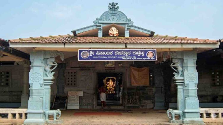 Front entrance view of the traditional Shri Vinayaka Temple in Guddattu, featuring a tiled roof, carved pillars with elephant figures, and a Kannada signboard.