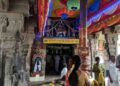 Interior of Bhoominathaswamy Temple in Mannachanallur showing carved stone pillars, a golden flagstaff (Dhvajastambha), and devotees praying near the sanctum.