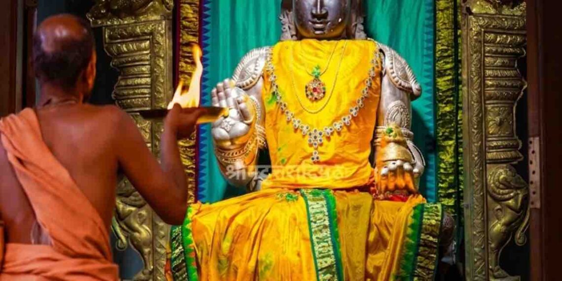 Idol of Lord Rogamochana Dhanvanthri at Uttaradi Math Mysore with a priest performing Aarti.