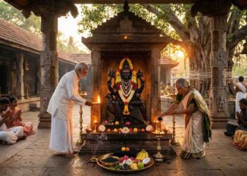 Traditional Shani Dev idol in a South Indian temple with devotees performing oil lamp rituals and offerings during Shanaischara Jayanti.