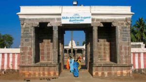 Main entrance gateway of the historic Nithya Kalyana Perumal Temple in Thiruvedanthai, Tamil Nadu, with devotees entering and a clear blue sky.