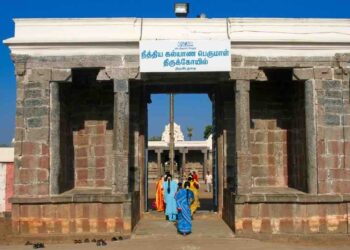 Main entrance gateway of the historic Nithya Kalyana Perumal Temple in Thiruvedanthai, Tamil Nadu, with devotees entering and a clear blue sky.