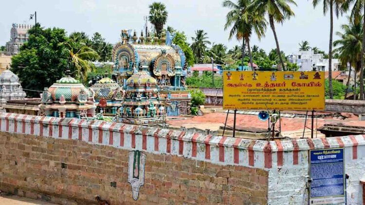 A detailed wide-angle photograph of the historic Uthamar Kovil temple complex near Tiruchirappalli, Tamil Nadu, showcasing several intricately decorated gopurams (temple towers) and mandapams.