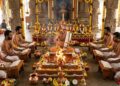 An authentic Vedic ritual in an ornate South Indian temple where a group of barefoot Hindu priests, clad in traditional white and gold clothing with bare torsos and distinct forehead markings, are performing a Navagraha Homa around a central sacred fire (Homa Kunda).
